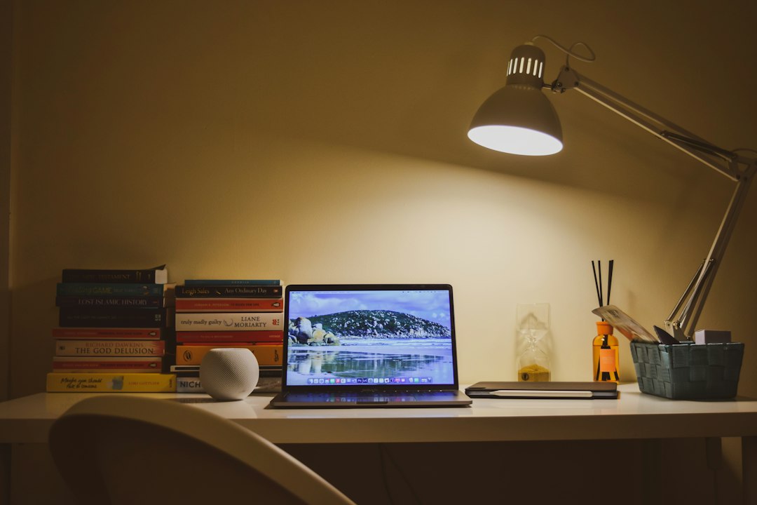 An open laptop on a white desk beside a desk lamp