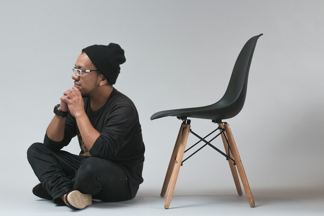A man sitting on a black chair at a desk with his legs stretched out